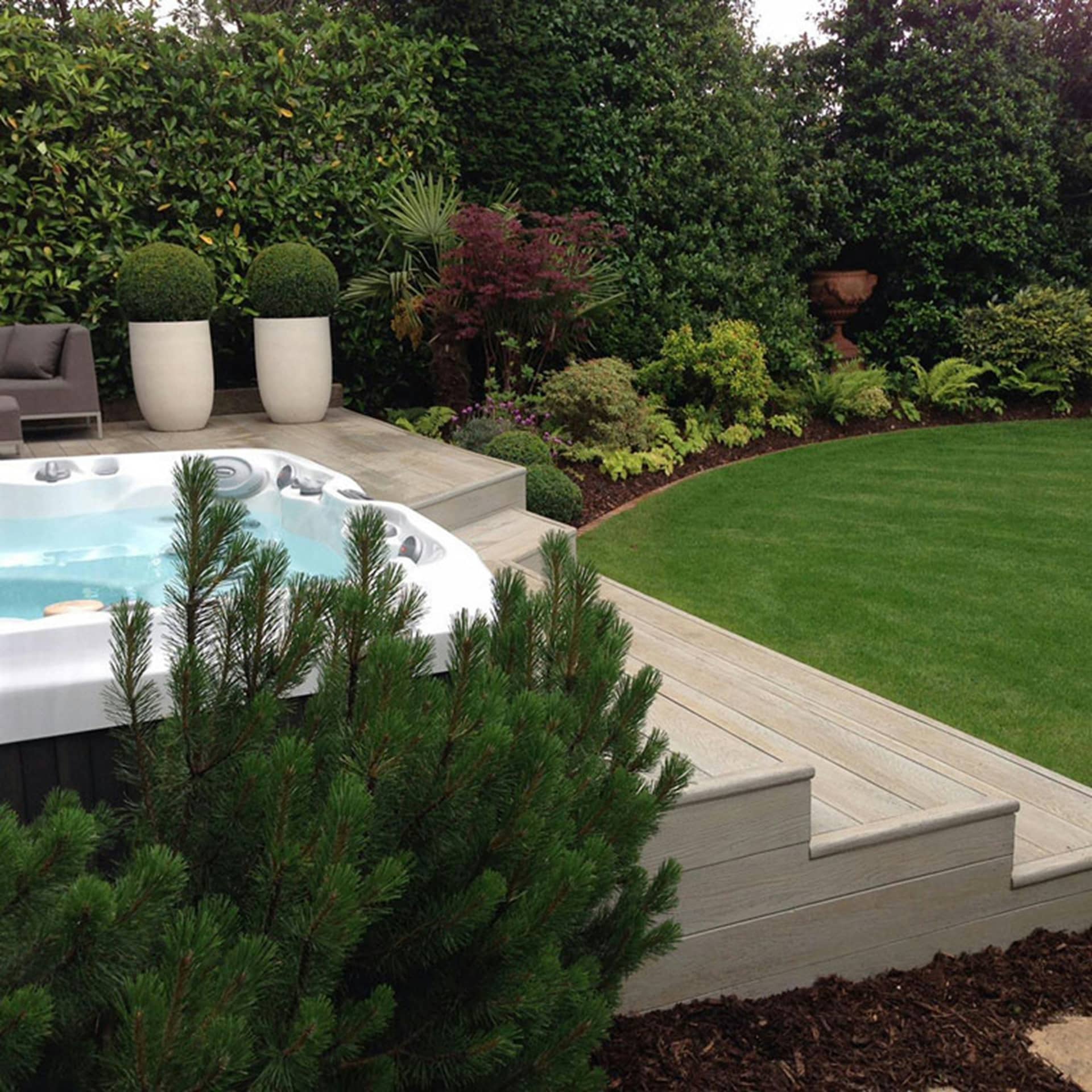 Hot tub on a decked terrace beside a garden lawn