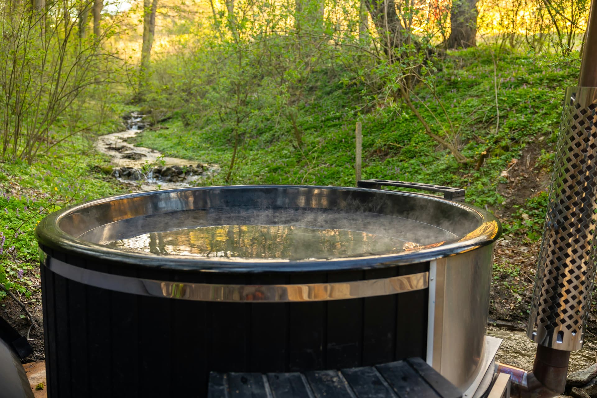 Wood-fired hot tub beside a woodland stream