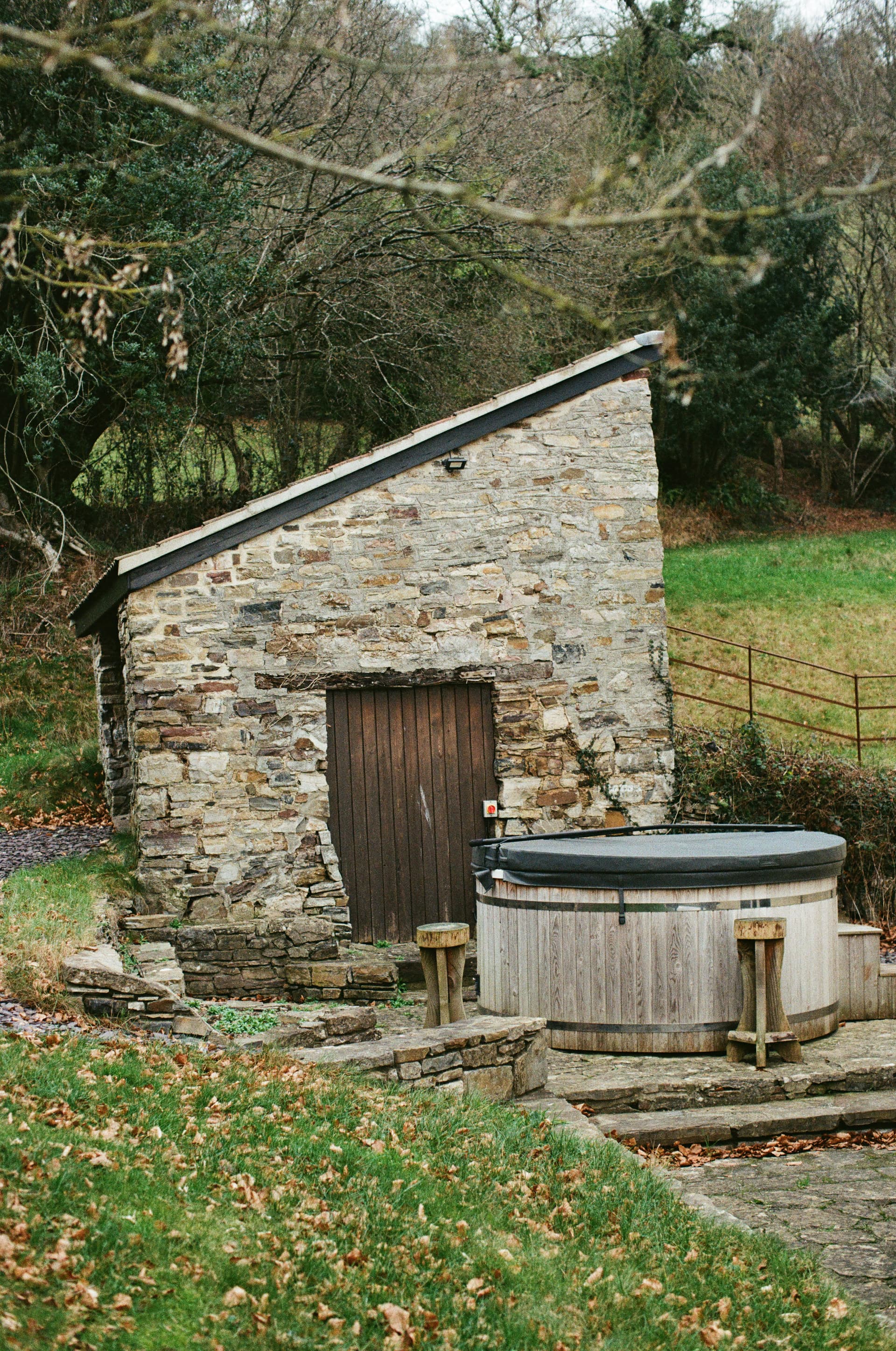 Wooden hot tub beside a stone cottage